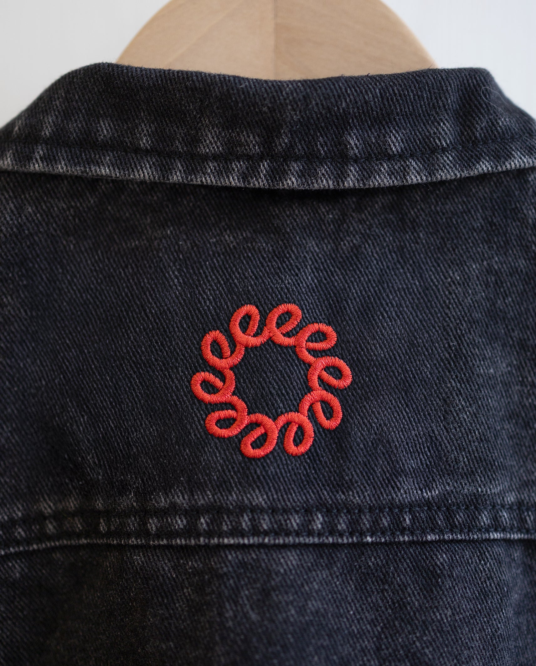 Black oversized denim jacket with a red embroidered TEEO design.